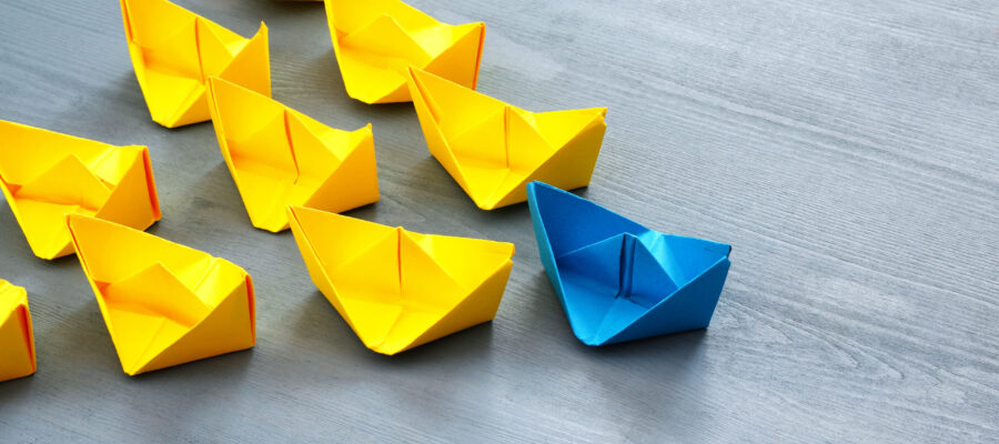 Leadership,Concept,With,Paper,Boats,On,Blue,Wooden,Background.,One